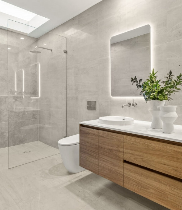 A renovated bathroom with a large, semi-open shower, a floating bench, and a mirror with backlighting.